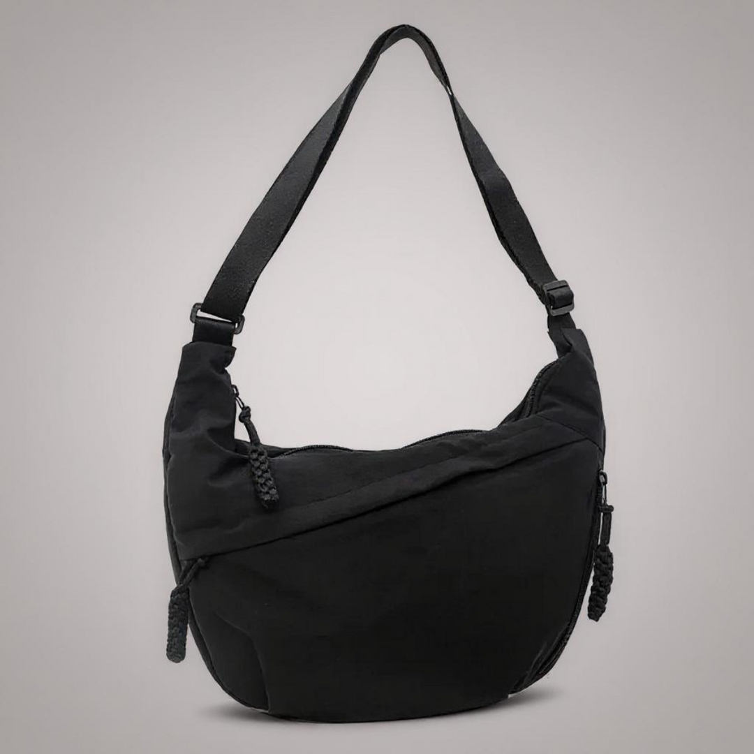 Red crescent-shaped nylon crossbody bag with a single adjustable strap and braided zipper pulls