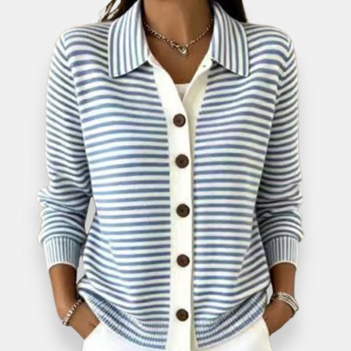 Woman wearing the collared cardigan in light blue and white stripes with brown buttons, white placket, ribbed cuffs, hands in pockets. 5