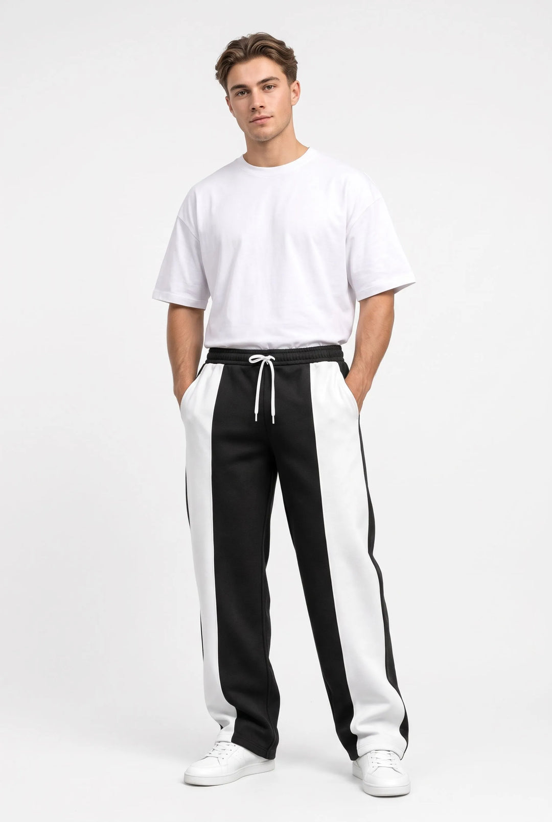 Full-length studio view of a model in black and white paneled sweatpants, hands in pockets 9