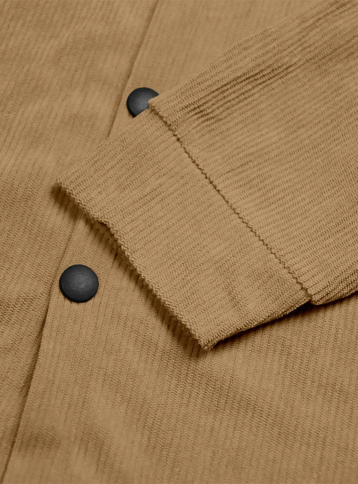 Detail of a tan shirt's ribbed cuff and black snap buttons on the front placket 9
