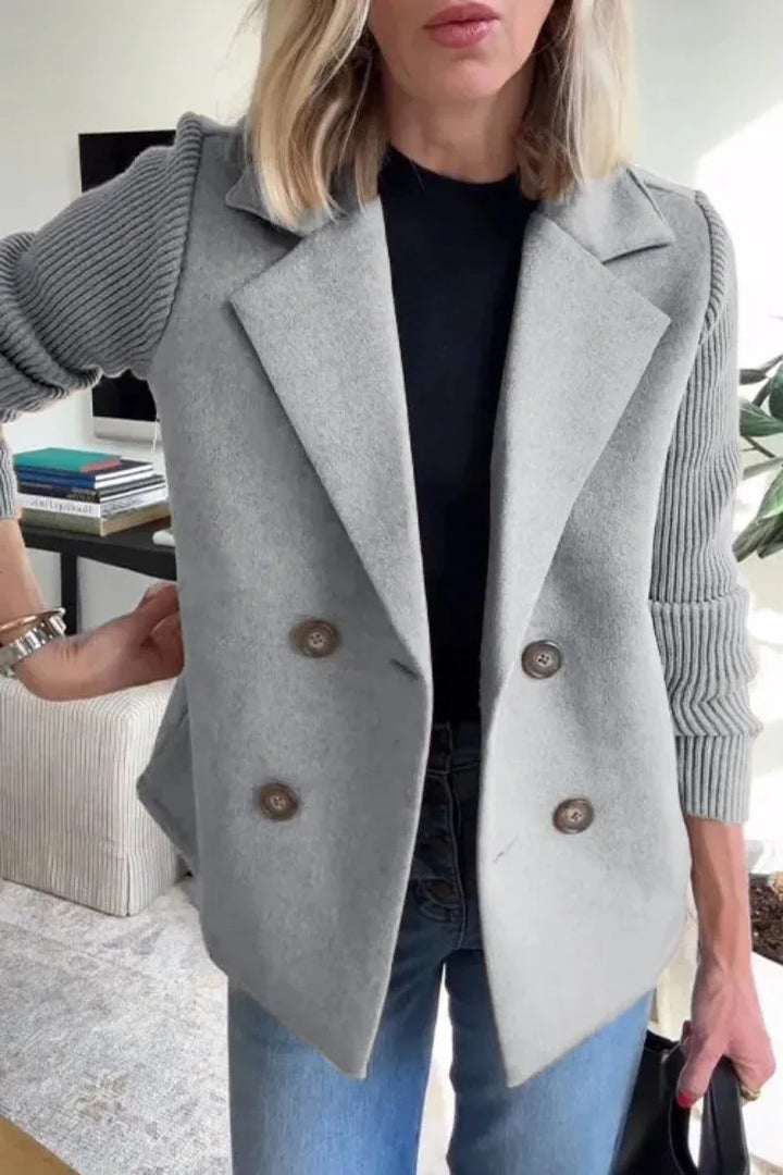 Close-up of gray jacket showing wide lapels, four buttons and ribbed knit sleeves over a black top 9