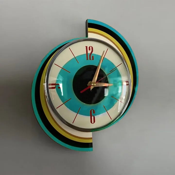 Swirl-shaped wall clock with curved teal, black, yellow and cream bands behind a chrome-rimmed dial with red numerals and gold hands.