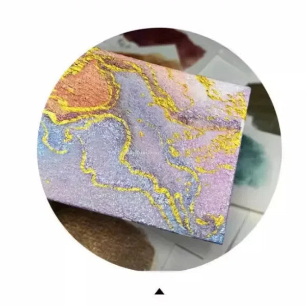 Detail of a painted card with marbled lavender, blue and orange washes outlined in shimmering yellow gold.