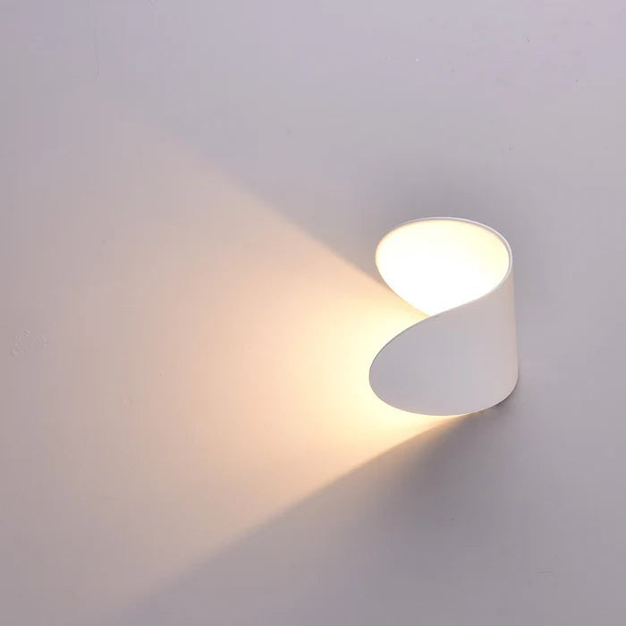 White wall light turned sideways on a pale wall, directing a warm beam of light diagonally across the surface.