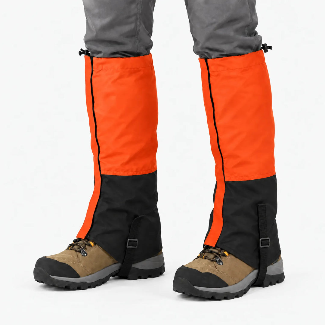 Orange and black gaiters worn over hiking boots, studio view showing the drawcord tops and straps under the boots. 12