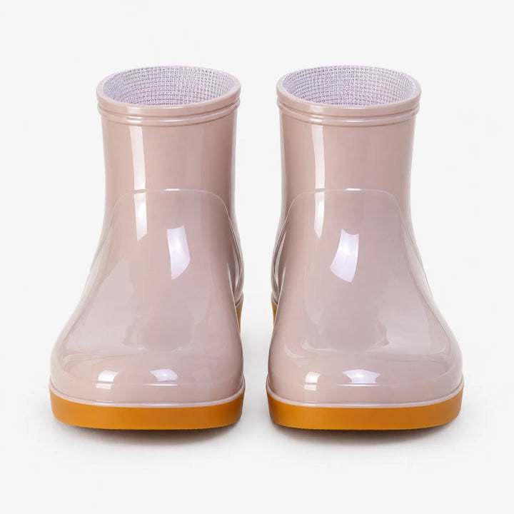 Front view of a pair of pale pink glossy ankle boots with orange soles and textured light lining visible inside. 6