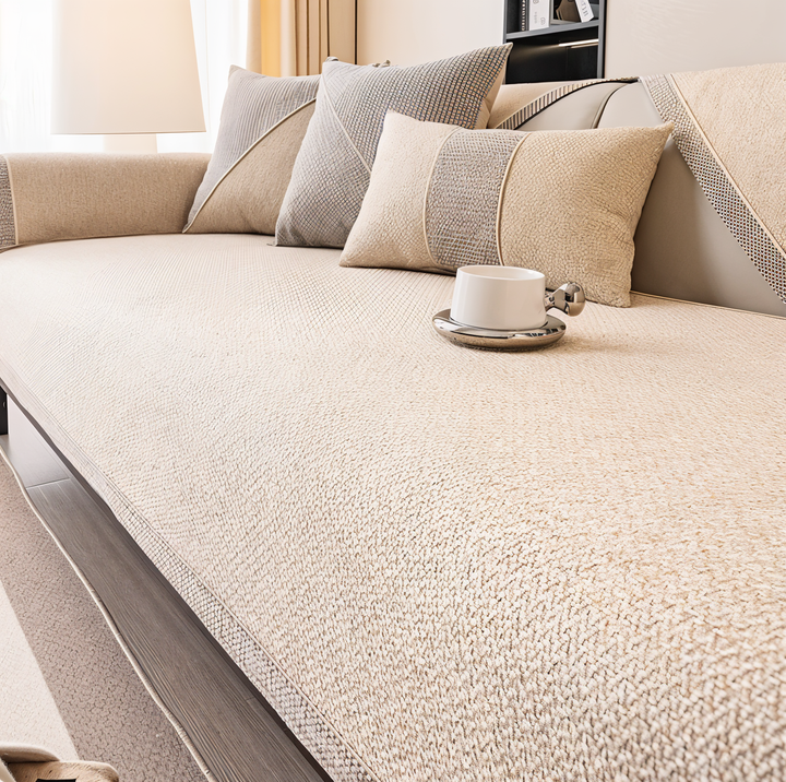 Cream version of the cover on a sofa, with cream and gray pillows and a white cup on the seat. 9