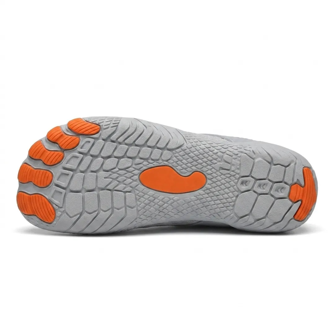 Underside of a gray sneaker showing the textured outsole with orange toe pads and an orange central oval.