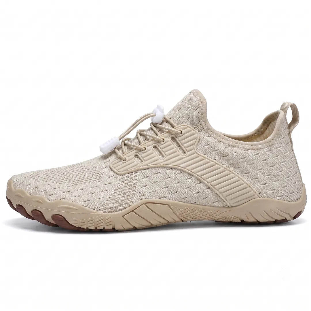 Side view of a beige knit barefoot sneaker with a matching sole, brown toe tips and white lace toggles.