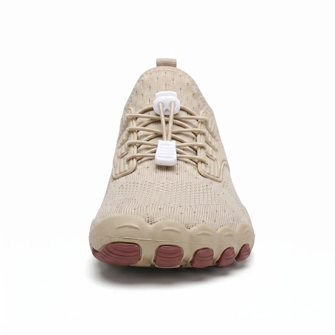 Front view of a beige sneaker showing the wide toe box, elastic laces and five brown toe-shaped sole pods. 23