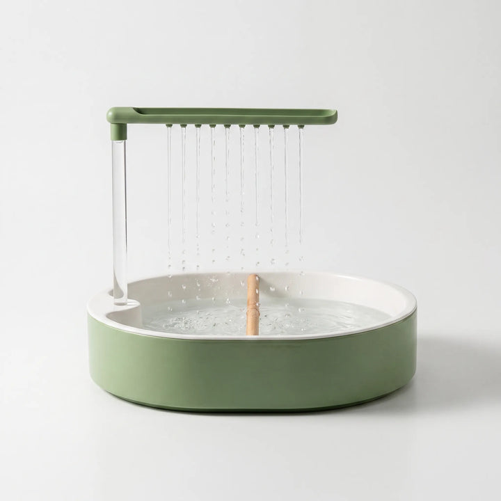 Green round bird bath with a white inner basin, a wooden perch and water streaming from ten spouts on an overhead arm, on a plain background. 1