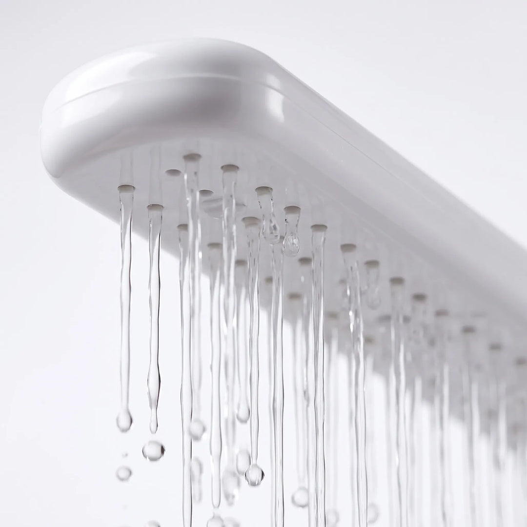 Close-up from below of the white spray bar's underside, showing small nozzles with thin streams of water running down. 3