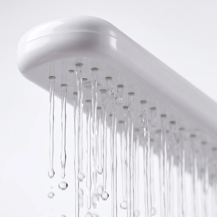 Close-up from below of the white spray bar's underside, showing small nozzles with thin streams of water running down. 3