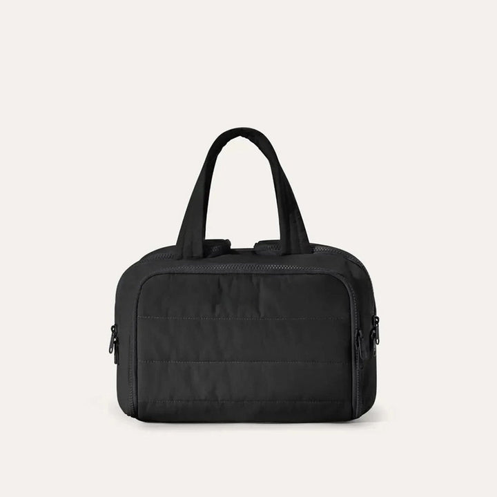 Quilted toiletry bag in black, front view, with two top handles and zipper pulls on both sides. 14