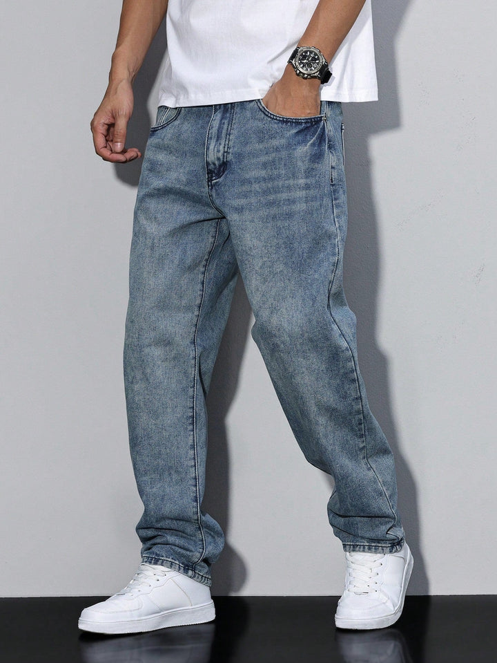 Men's baggy jeans in faded mid-blue denim, front angled view on a model with white sneakers.
