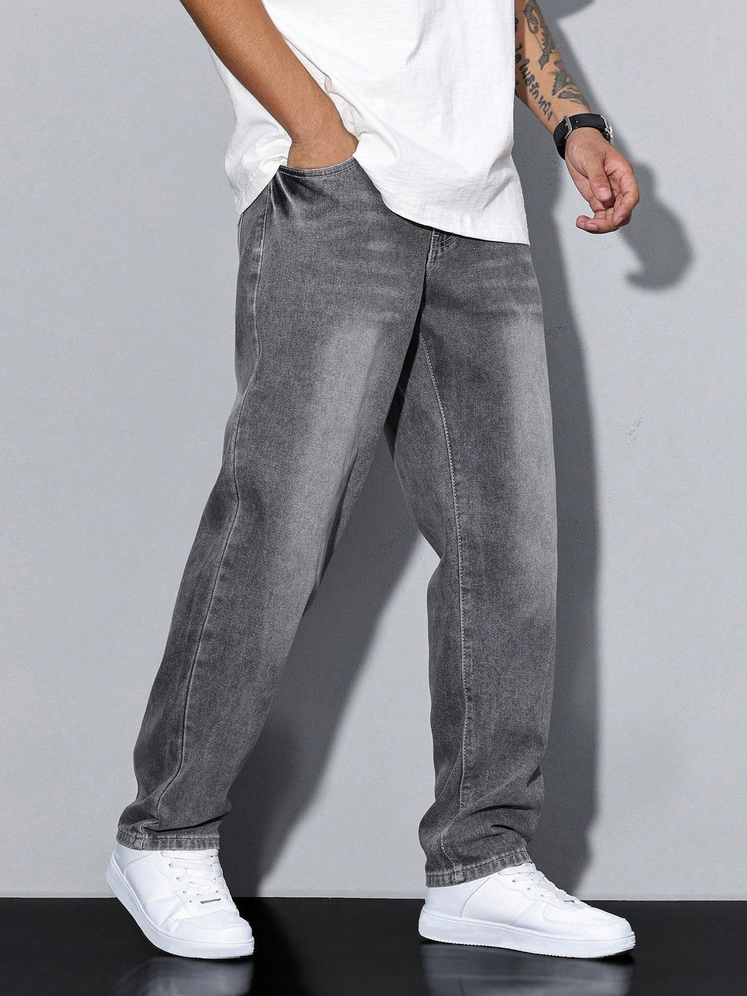 Men's baggy jeans in gray faded denim, another view on a model walking with a hand in the pocket.