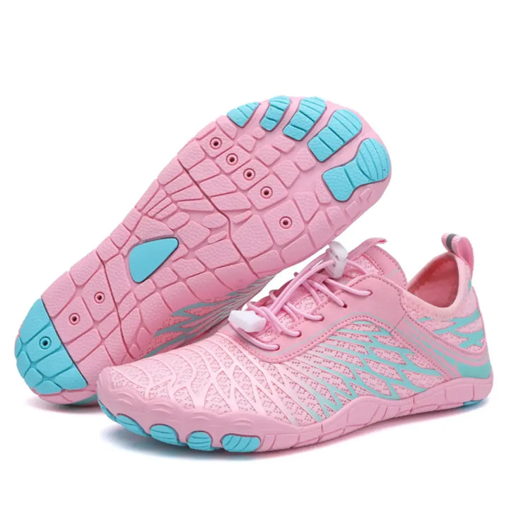 Pink barefoot shoes with turquoise accents, one shoe tilted to show the turquoise-toed sole, the other upright with pink bungee laces.