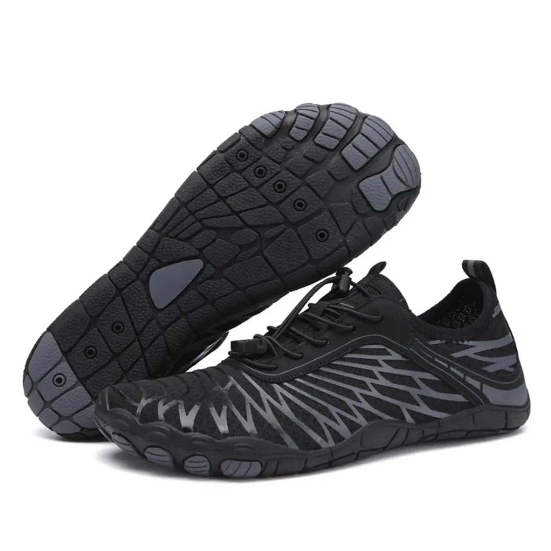 Black barefoot shoes with gray accents, one shoe tilted to show the gray-toed lugged sole, the other upright with black bungee laces.