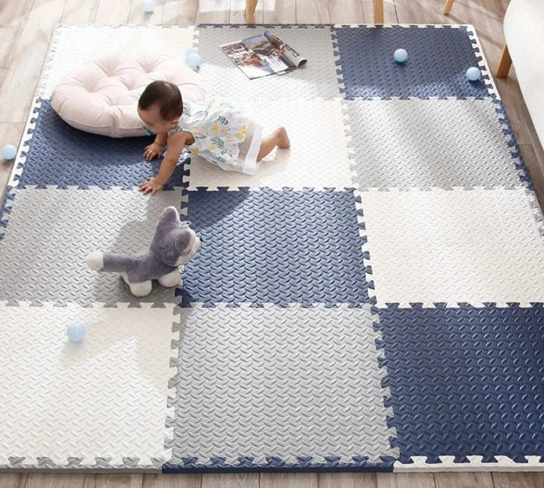 Baby crawling across a navy, gray and cream interlocking foam mat.