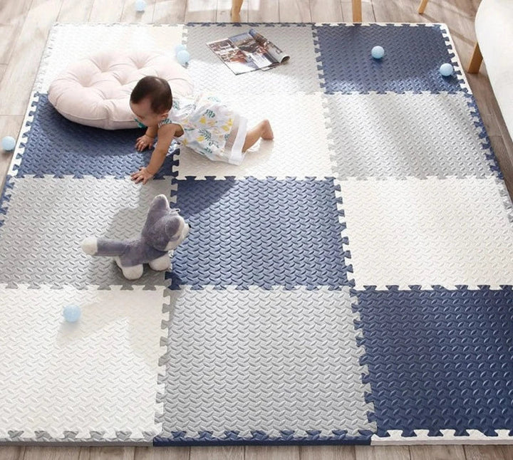 Baby crawling across a navy, gray and cream interlocking foam mat.