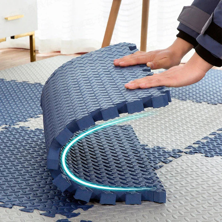 Hands bending a navy foam tile into a curve over a blue and gray mat.