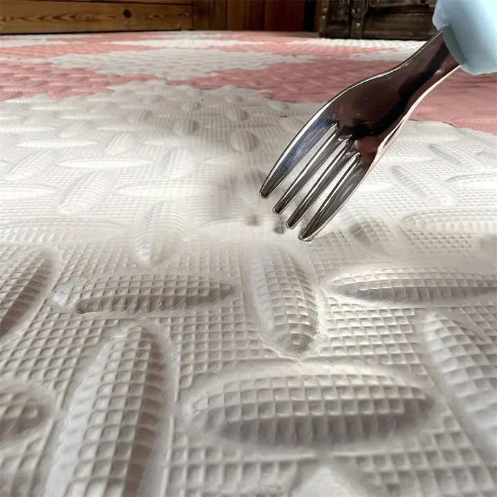 Close-up of a fork pressing into the textured surface of a cream foam tile.