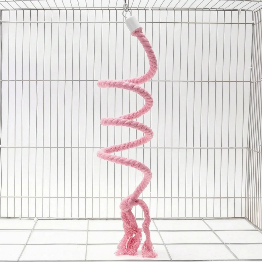 Pink version of the spiral rope perch hanging from a small hook in a wire cage, with a knot and frayed ends. 6