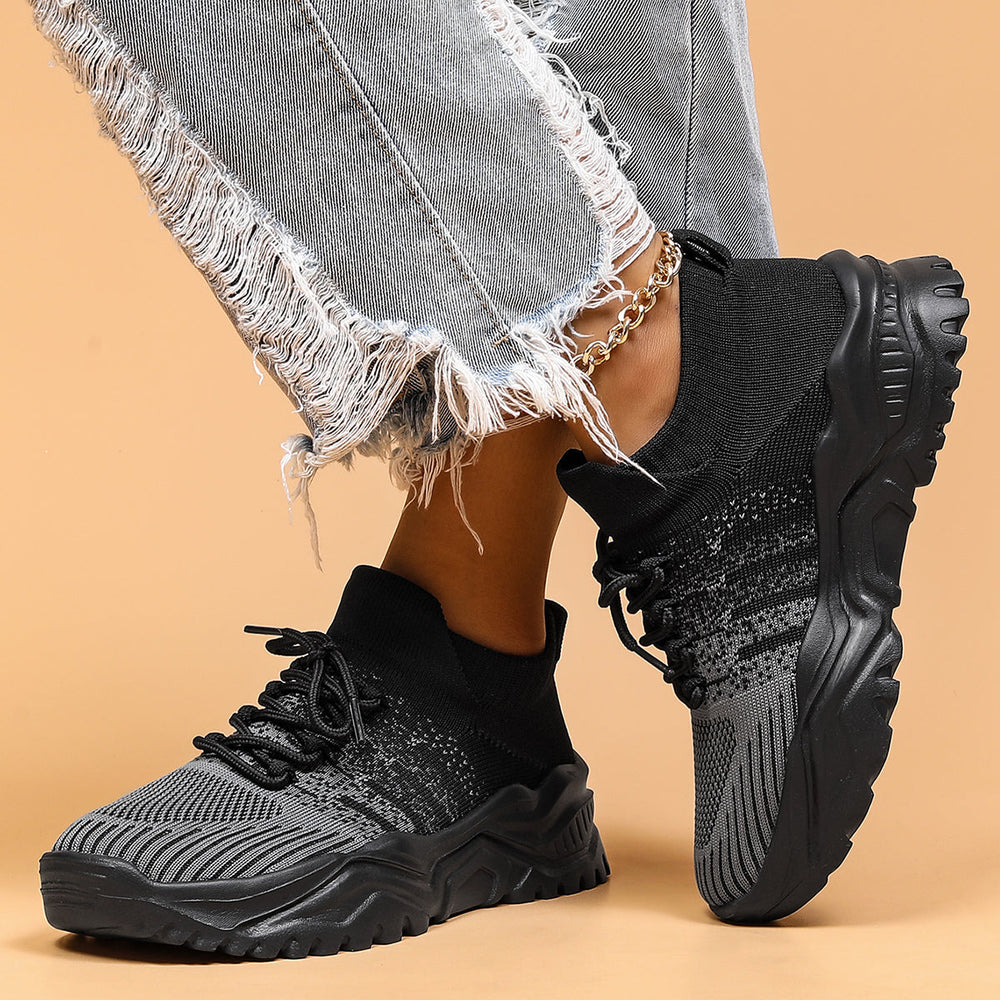 Black and gray knit sock sneakers with thick lug soles, front view.