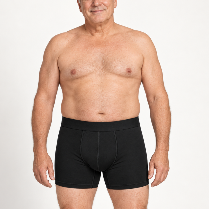 Smiling older shirtless man wearing black boxer briefs with a wide waistband, shown from the front against a white background. 2