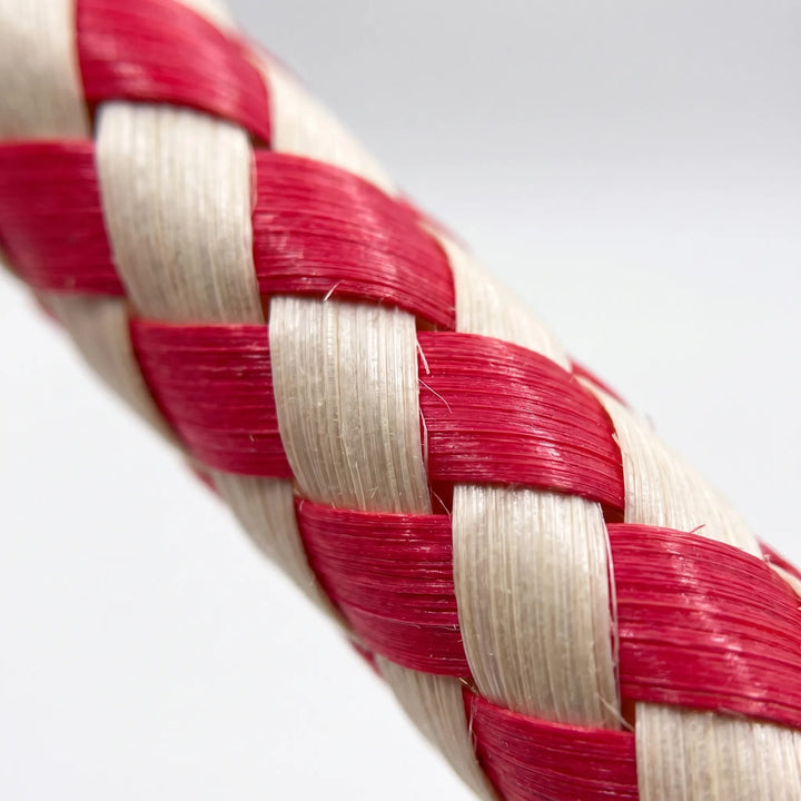 Extreme close-up of the red and natural-colored woven strips, showing the fine fibers and interlaced braided texture of the tube. 3