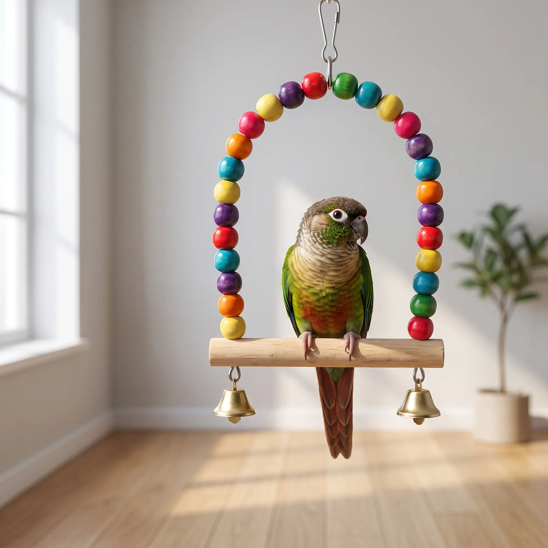 A green-cheeked conure with a rust-colored tail sits on the swing's wooden bar, which hangs in an empty room with a wood floor. 3
