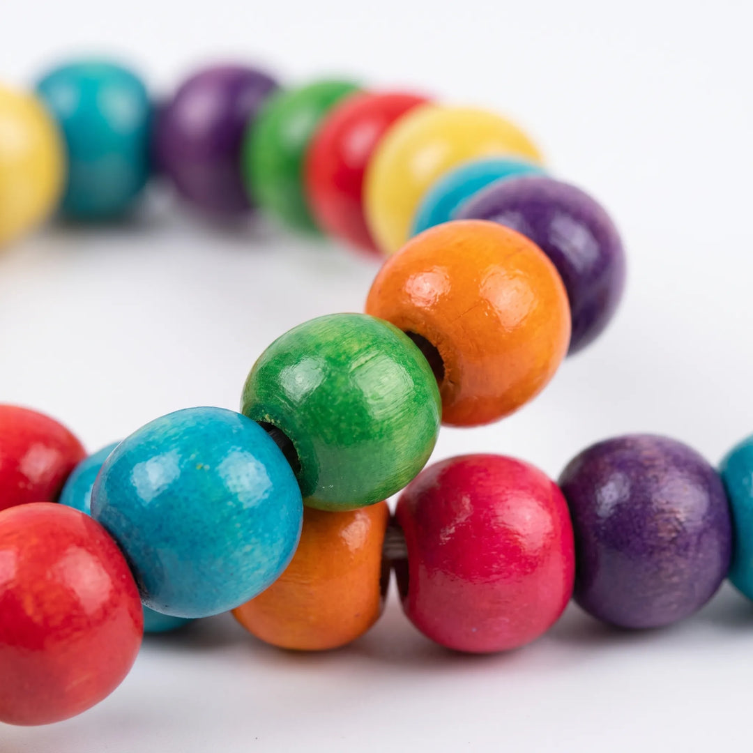 Close-up detail of glossy dyed wooden beads in red, blue, green, orange, pink and purple threaded along the swing's arch. 4