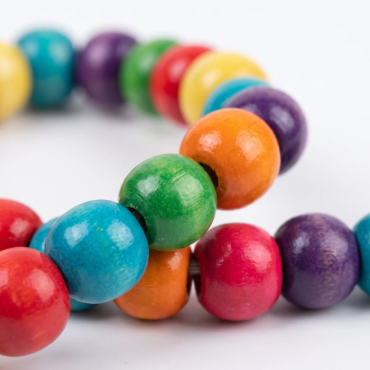 Close-up detail of glossy dyed wooden beads in red, blue, green, orange, pink and purple threaded along the swing's arch. 4