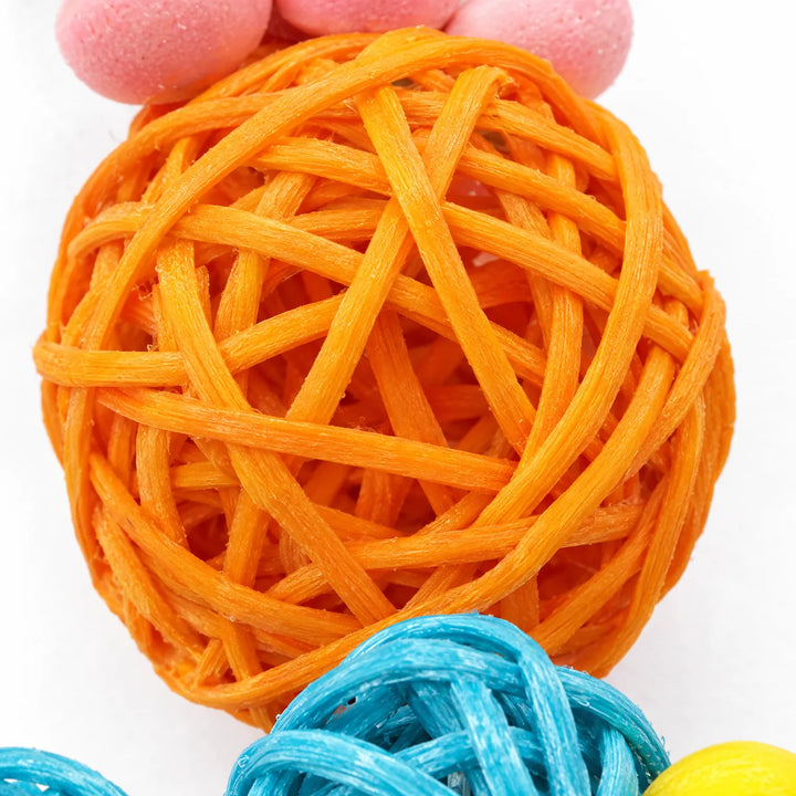 Close-up of a woven orange rattan ball with a pink flower piece above and blue rattan balls below, showing the texture. 3
