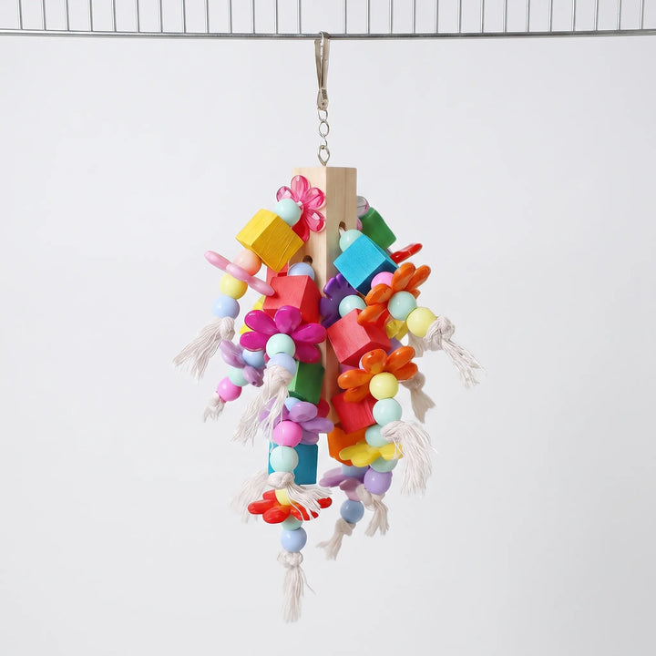 Another front view of the toy hanging from a wire, showing its colorful blocks, flowers, beads and rope tassels. 4