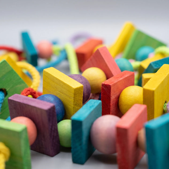 Close-up detail of the brightly dyed wooden blocks and round beads threaded together with colorful braided rope. 4