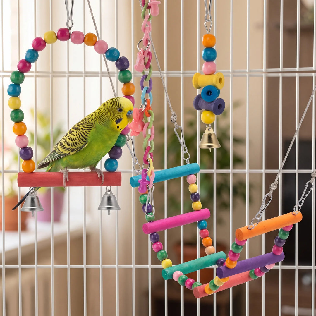 A green and yellow budgie perches on the beaded swing inside a cage, with ladders and hanging toys beside it. 2