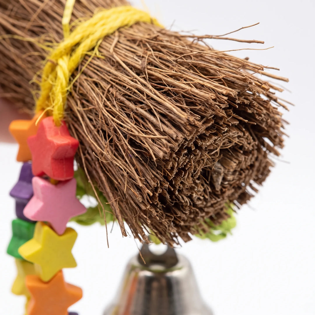 Close-up of the bundled brown natural fibers tied with yellow cord, with colorful wooden star beads and a bell below. 2