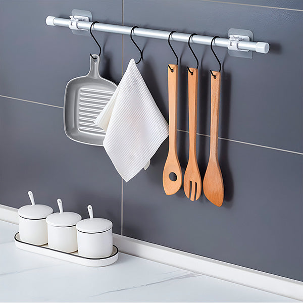 Clip-on storage hooks on a gray kitchen wall holding a grill pan, dishcloth and wooden utensils.