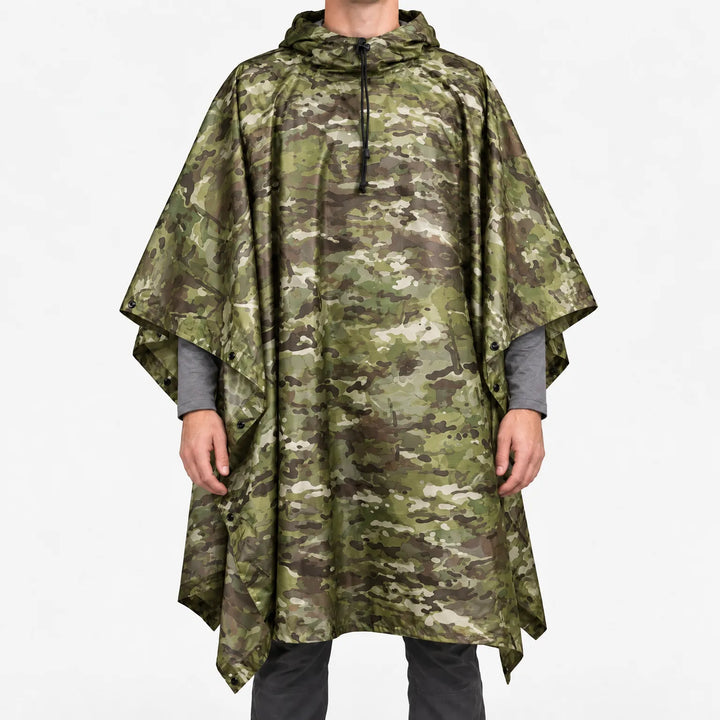 Front view of a hooded poncho in green, brown and tan camouflage worn over a gray long-sleeve shirt, with snaps along the sides. 7