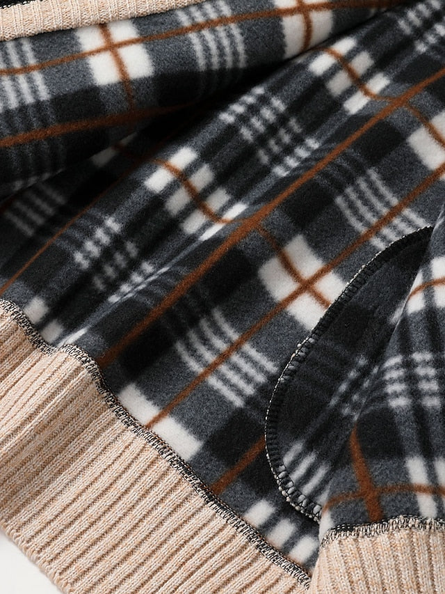Detail of soft black, white and brown plaid fleece with stitched edges and a beige ribbed hem.
