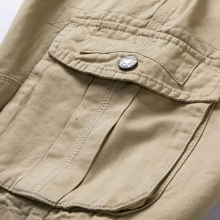 Close-up of a khaki cargo pocket with a metal snap button, flap and double-stitched seams.
