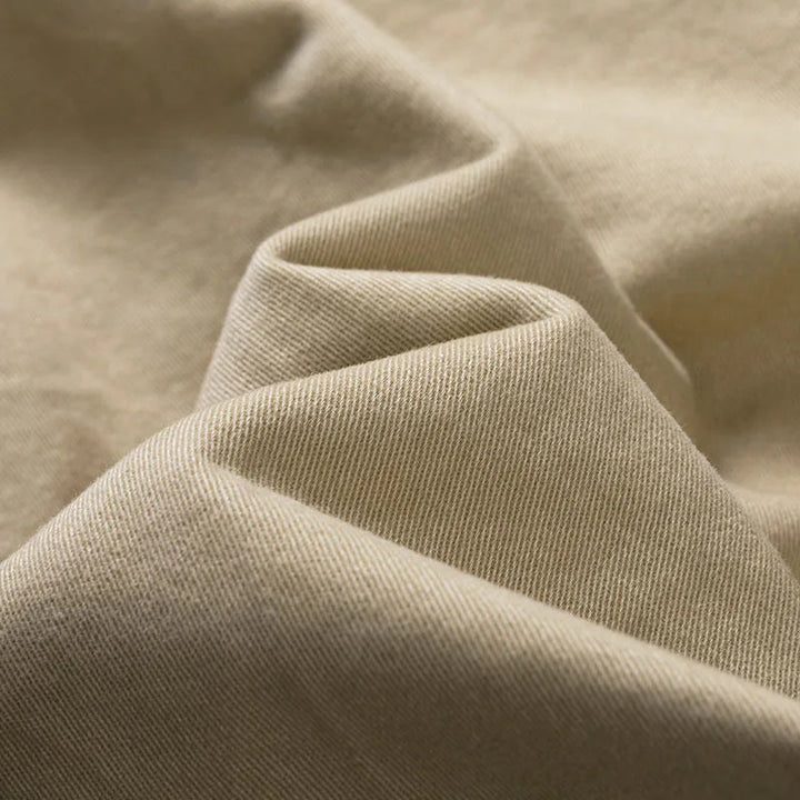 Close-up of soft folded khaki twill fabric showing the fine diagonal weave of the shorts material.