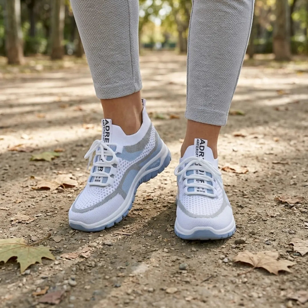 Pair of white and light blue mesh sneakers worn by a woman in gray leggings on a leafy park path. 2
