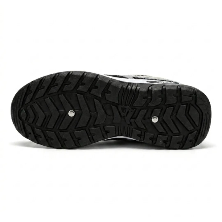 Bottom view of the sneaker showing the black rubber outsole with deep chevron tread pattern and two small metal studs. 45