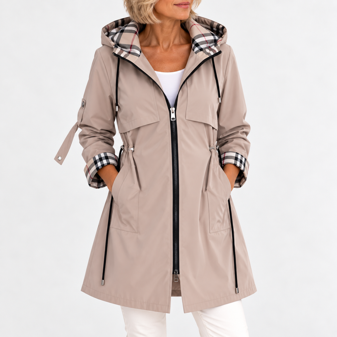 Front view of the beige hooded coat on a model, hands in pockets, plaid lining visible at hood and cuffs 2