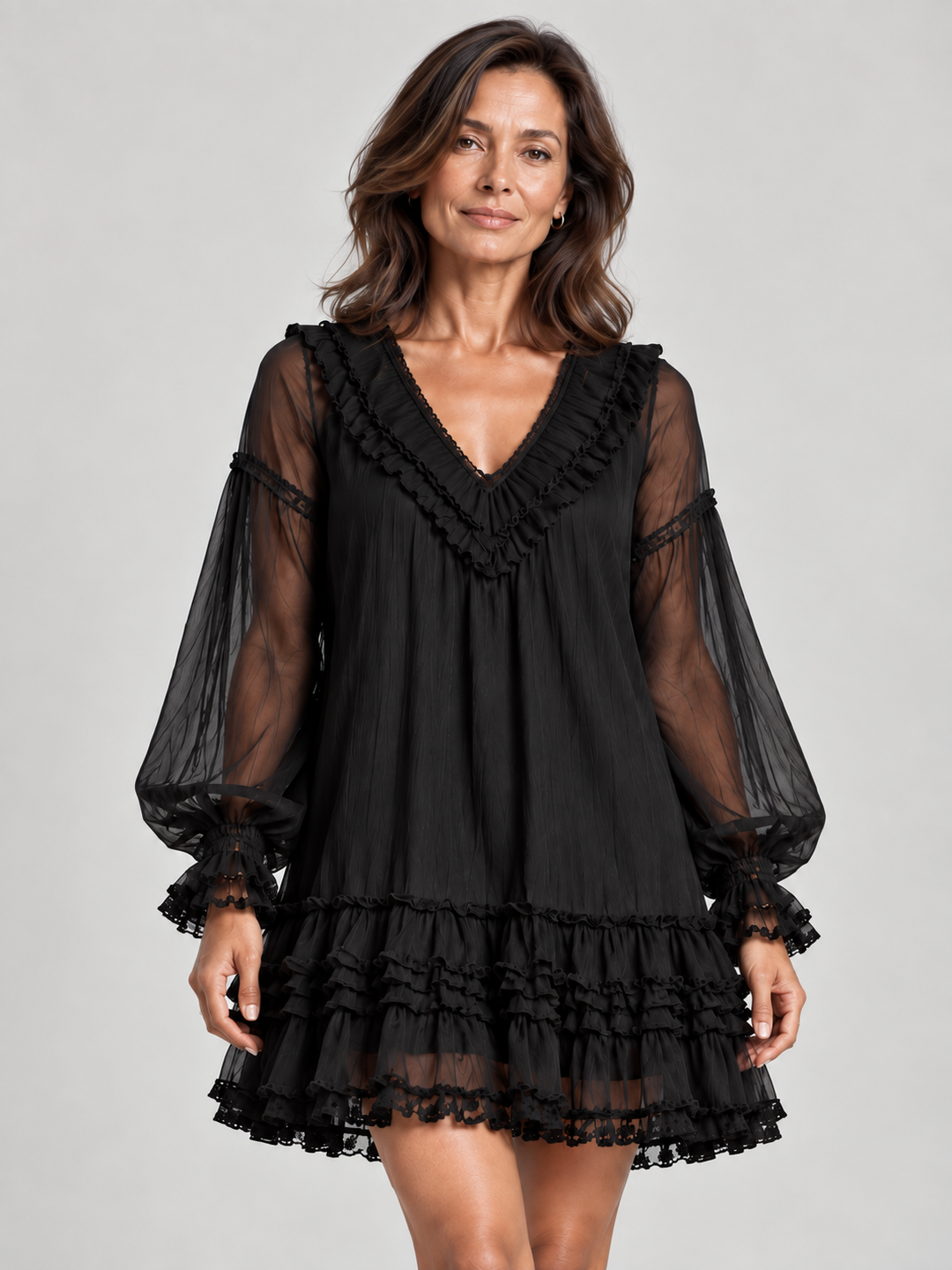 Woman wearing the black mini dress in a close front view, showing the ruffled V-neckline, sheer balloon sleeves and tiered hem. 1