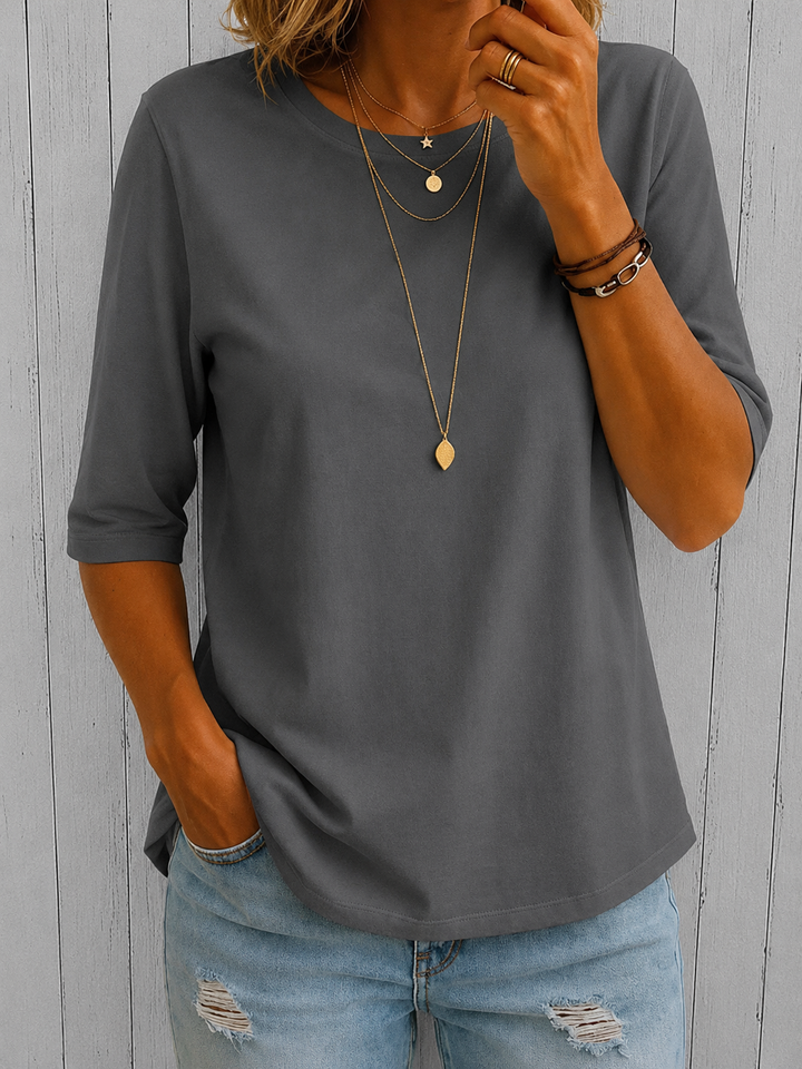 Medium gray half-sleeve tee with a crewneck and layered gold necklaces, another view.