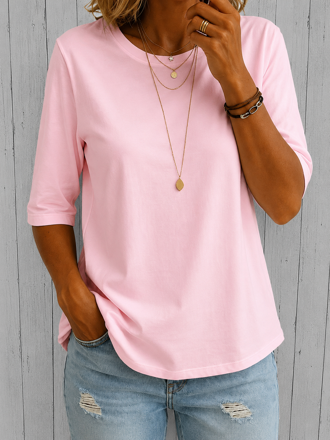 Woman wearing the soft pink crew-neck tee with longer half sleeves and a curved hem, another view.