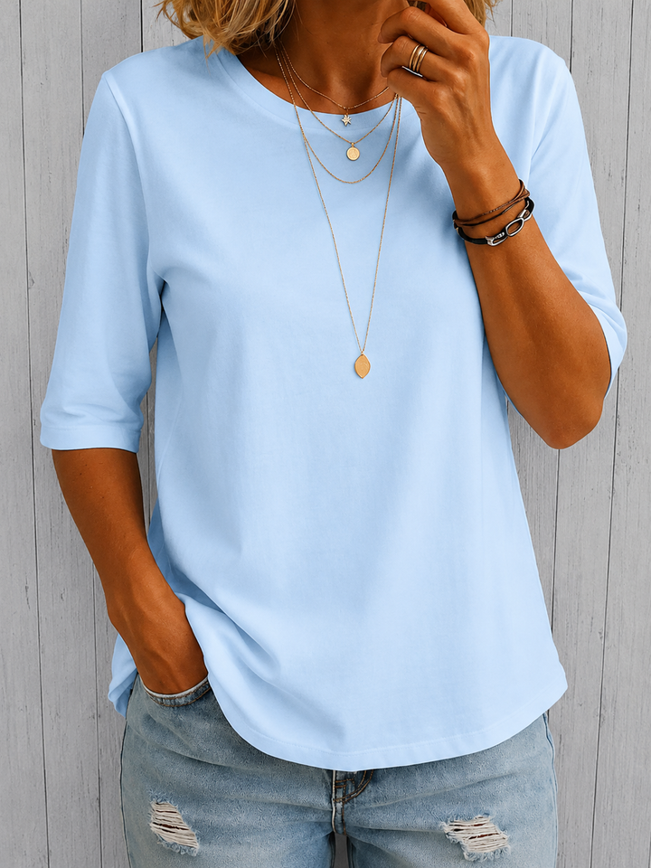 Light blue half-sleeve tee with a crewneck and layered gold necklaces, another view.